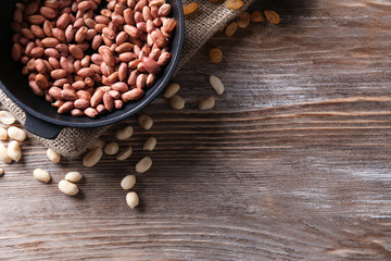 Frying pan with roasted peanuts on wooden background