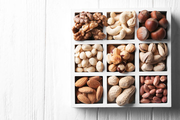Box with different nuts on white wooden background