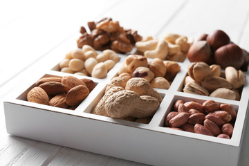 Box with different nuts on white wooden table