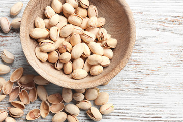 Bowl with pistachio nuts on wooden background