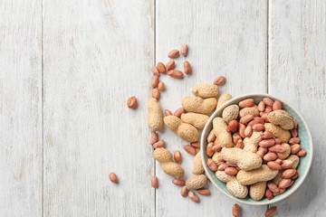 Fototapeta na wymiar Bowl with peanuts on wooden background