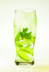 summer cold drink mojito lime and mint with ice and soda with drops on a glass on a white background
