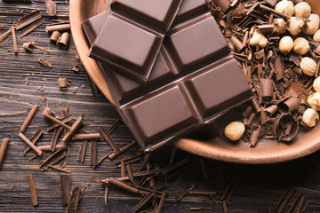 Plate with chocolate curls and hazelnuts on table