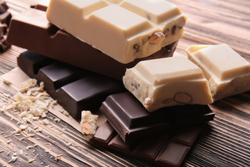 Different chocolate bars with curls on wooden table