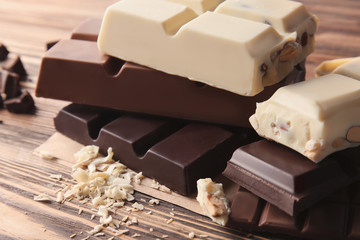 Different chocolate bars with curls on wooden table