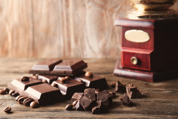 Pieces of black chocolate with coffee beans on wooden table