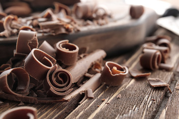 Chocolate curls on wooden table, closeup