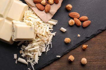 Slate plate with white chocolate curls and nuts on table