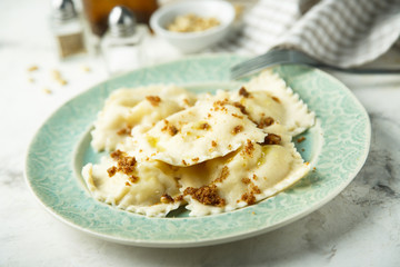 Homemade ravioli with fried bread crumbs, soft cheese and pine nuts