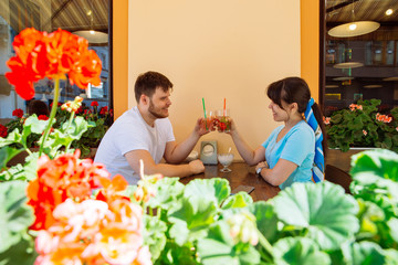 couple sitting in summer cafe drinking cool drinks and talking