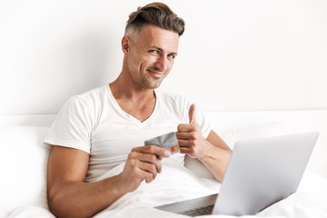 Happy man using laptop computer and showing thumbs up