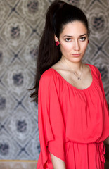 portrait of beautiful girl in  silk orange dress, old  decorated wall background