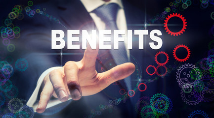 A businessman pressing a Benefits business concept on a graphical display of cogs