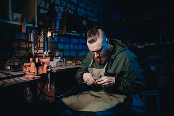 Modern man worker performs work with metal, grinds an electric machine in garage, repairs car