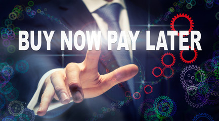 A businessman pressing a Buy Now Pay Later business concept on a graphical display of cogs
