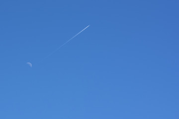 The plane flies away from the moon in the distance