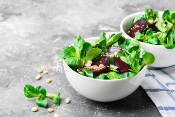 Salad of beet young shoots of green lettuce and nuts in a white bowl. Proper nutrition. Vegetarianism. Close-up. Copy space