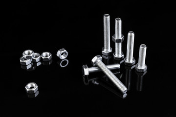 Metal chrome bolts and nuts isolated on black background with copy space.