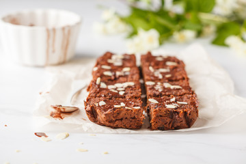 Vegan sweet potato brownie with almonds  on white table. Healthy vegan food concept.