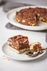 Raw vegan chocolate cake with nuts and chocolate in white plate. Healthy vegan food concept.