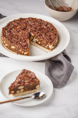 Raw vegan chocolate cake with nuts and chocolate in white plate. Healthy vegan food concept.