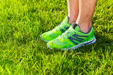 Sports shoes sneakers on a fresh green grass field. Sport equipment bottom view. Sports in the open...