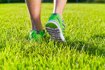 Sports shoes sneakers on a fresh green grass field. Sport equipment bottom view. Sports in the open...