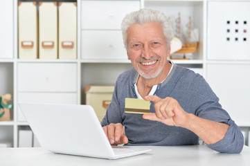 Fototapeta na wymiar senior man with laptop holding credit card