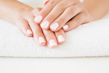 Young, perfect woman's hands with white nails on towel. Care about nails and clean, soft, smooth skin. Manicure, pedicure beauty salon.