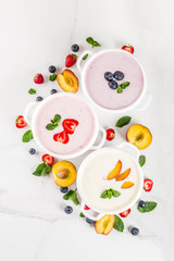 Summer healthy diet dinner, vegan food, dessert, various sweet creamy fruit & berry soups - strawberry, peach, blueberry, white marble background  top view copy space