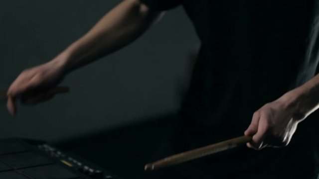 Close up shot of man's hands drum sticks on sampler and electronic pads