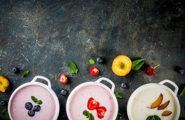 Various sweet creamy fruit & berry soups - strawberry, peach, blueberry, dark blue concrete background  top view copy space