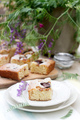 Pieces of fruit pie with pieces of plums and peach and a bouquet of flowers on a wooden table. Rustic style.