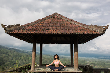 woman practicing yoga in the traditional balinesse gazebo
