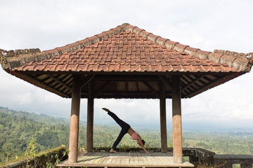 woman practicing yoga in the traditional balinesse gazebo