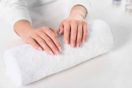 cropped image of woman holding hands for manicure procedure at table with towel in beauty salon