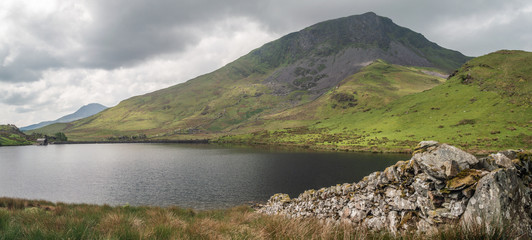 A dry stone wall leads to the fishing lake of Llyn y Dywarchen in the Snowdonia National Park. The beautiful mountain y Garn is in the distance.