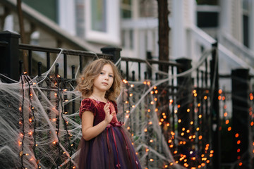 Fototapeta na wymiar Little girl in a fairy costume walking on the streets during Haloween