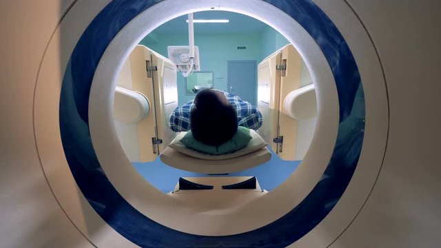 Male patient is moving into a CAT-scanner. Medical equipment: computed tomography machine in diagnostic clinic