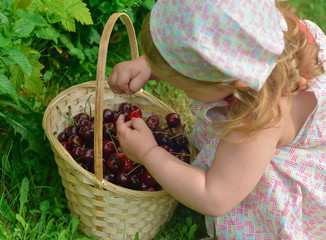 A girl in a dress is holding a cherry in her hands