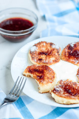 Cottage cheese pancakes with sour cream and strawberry jam on white background, breakfast or lunch