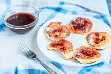 Cottage cheese pancakes with sour cream and strawberry jam on white background, breakfast or lunch