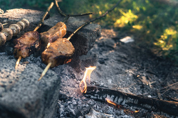 mushrooms and meat on skewers made of wood, twigs, cooking at the stake, bonfire, camping concept