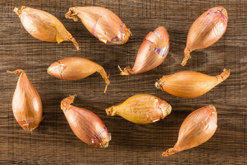 Long golden shallots top view isolated on brown wood background.