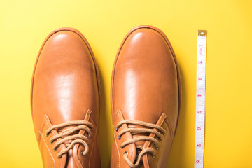 brown shoes and measuring tape on yellow background