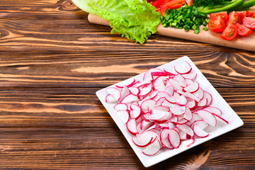 Fresh sliced vegetables on a salad: radish, cherry, greens, cucumber, red pepper. Space for text or design