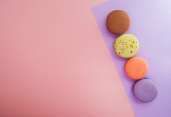 Macarons of different color on multicolored background.