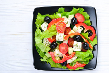 Greek salad on a white wooden background. Space for text or design.