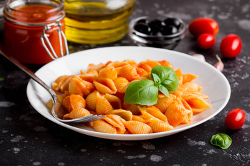 Italian shell pasta with tomato sauce, olives and Basil, classic food