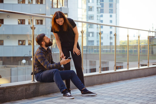 Couple using smart phone together while sitting on steps in city